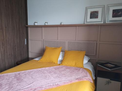 Una cama con dos almohadas amarillas encima. en Un confortable hogar en el corazón de la CDMX., en Ciudad de México