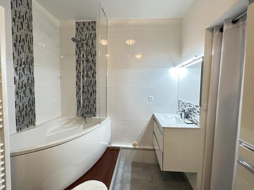 une salle de bain blanche avec une baignoire et un lavabo dans l'établissement Grand T3 Bis chaleureux avec terrasse, ascenseur et parking gratuit, à deux pas de la place Castellane - FR-1-309-151, à Port-Vendres