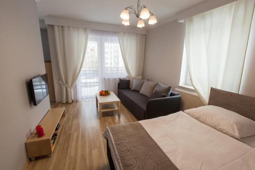 een slaapkamer met een bed, een bank en een raam bij Apartament Klonowa in Kielce