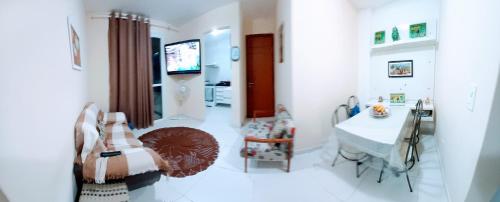 Apartamento temporada com garagem, Wi-Fi, Netflix في غواراباري: غرفة بيضاء مع طاولة وتلفزيون