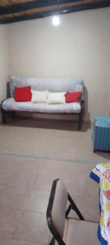 un sofá con almohadas rojas y blancas en una habitación en La georgi 2 en Luján de Cuyo