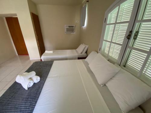 a bedroom with a large white bed with towels on it at Hotel Fazenda Bonanza in Engenheiro Paulo de Frontin