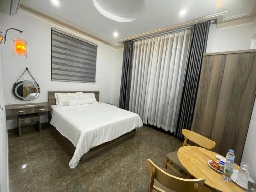 a bedroom with a bed and a table and a desk at Nam Anh Homestay in Bao Loc