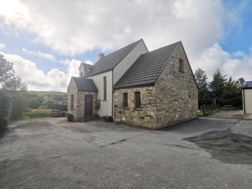 una pequeña casa de piedra con entrada en Comfortably Crolly Holiday Home, en Letterkenny