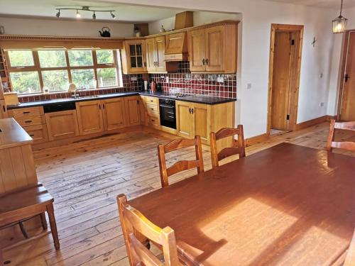 a kitchen with wooden cabinets and a wooden table with chairs at Comfortably Crolly Holiday Home in Letterkenny
