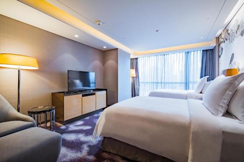 a hotel room with a bed and a flat screen tv at Four Seasons Hotel Shenzhen in Shenzhen