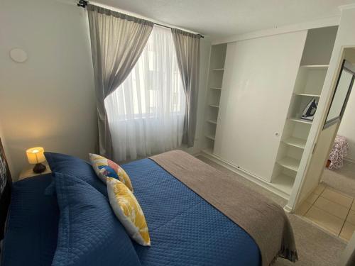 Un dormitorio con una cama azul y una ventana en Fantástico departamento en la Serena al lado de la playa, en La Serena