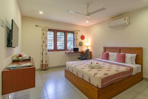 a bedroom with a bed and a desk and a window at StayVista at Anjali with Free Breakfast & Terrace Access in Kozhikode