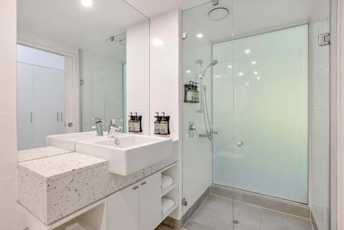 a white bathroom with a sink and a shower at Peppers Beach Club in Port Douglas