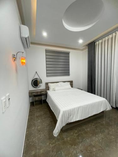 a bedroom with a white bed and a window at Nam Anh Homestay in Bao Loc
