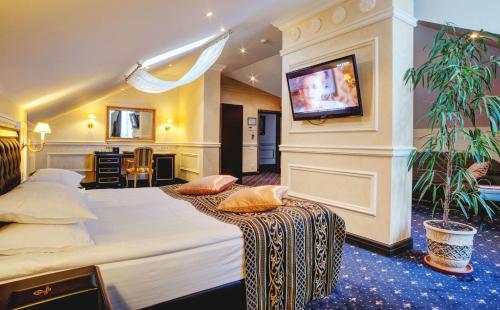 a bedroom with a large bed with a tv on the wall at Villa Le Premier - Maestro in Odesa