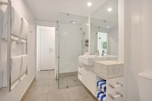 a white bathroom with a sink and a shower at Peppers Beach Club in Port Douglas