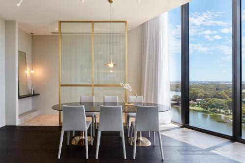 a dining room with a table and chairs and a large window at Eos by SkyCity in Adelaide