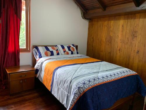 a bedroom with a bed and a wooden wall at MY HOUSE IN MACAS, MIRADOR AL UPANO in Macas