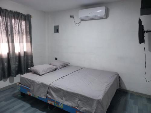 a bedroom with a bed and a air conditioner at Habitación Suites Playas in Playas
