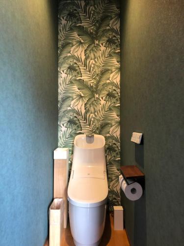 a bathroom with a toilet with a green wallpaper at B&B Sampark in Shirahama