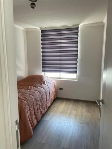 a bedroom with a bed and a window with blinds at Departamento con vista al mar in Iquique