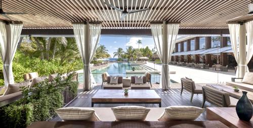 an outdoor patio with tables and chairs and a pool at Park Hyatt Maldives Hadahaa in Gaafu Alifu Atoll