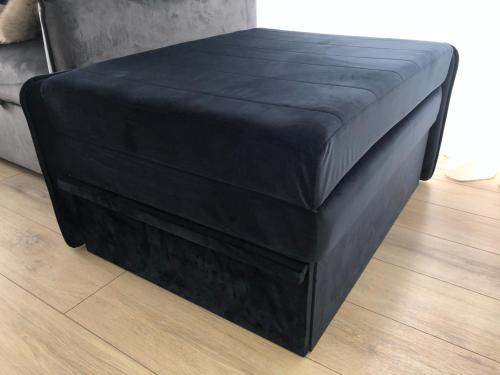 a black ottoman sitting on the floor in a room at SUN HOME in Palanga