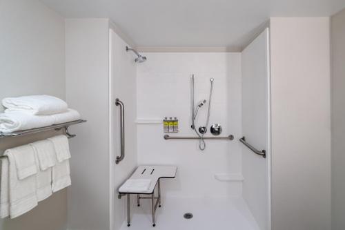 uma casa de banho branca com um chuveiro e um banco em Holiday Inn Express Hotel & Suites Bluffton at Hilton Head Area, an IHG Hotel em Bluffton