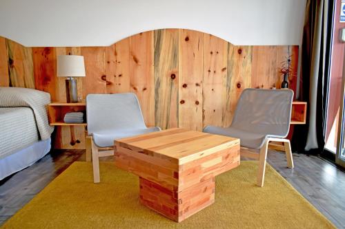 a bedroom with two chairs and a wooden wall at Vides del Rio Suites in Valle de Guadalupe
