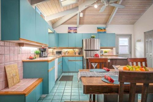 uma cozinha com armários azuis e uma mesa e cadeiras em Beautiful Spacious Home in Paradise em Waikoloa Village