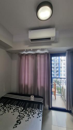 1 dormitorio con 1 cama y ventana con balcón en Sea Residences by EZ Stay, en Manila
