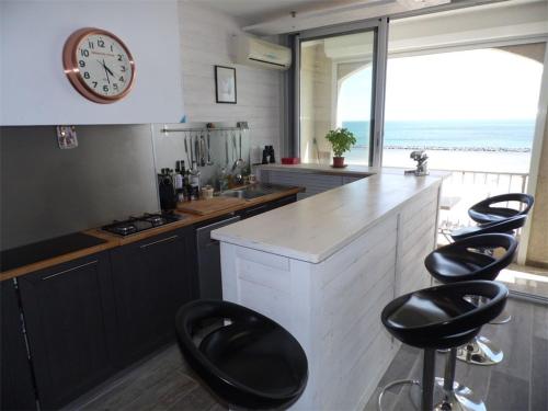 une cuisine avec des chaises noires et un comptoir avec une horloge dans l'établissement Grau d'Agde : Appartement climatisé 2 chambres à 20m de la plage - FR-1-423-172, au Grau-dʼAgde