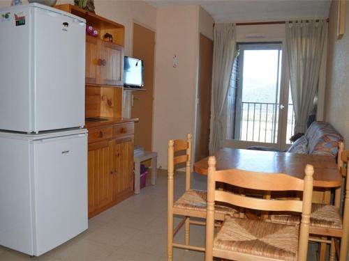 une cuisine avec une table et un réfrigérateur blanc dans l'établissement Appartement cosy pour 4 avec balcon et cuisine équipée - FR-1-593-37, aux Angles
