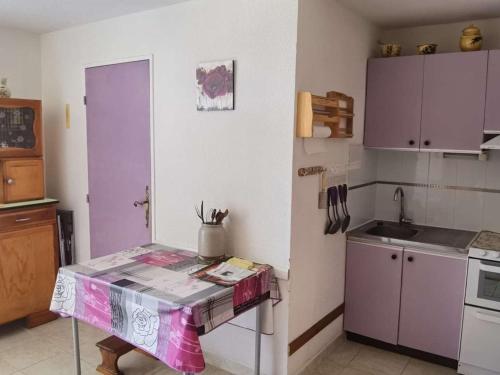 une cuisine avec des placards violets et une table. dans l'établissement Appartement 2 Pièces avec Cabine, Loggia et Parking Privé - 4 Couchages, Marseillan - FR-1-326-723, à Marseillan
