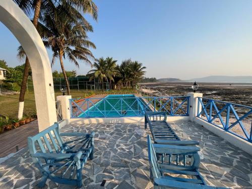two blue chairs sitting on a patio near the beach at Sea Breeze Beach Resort Murud in Murud