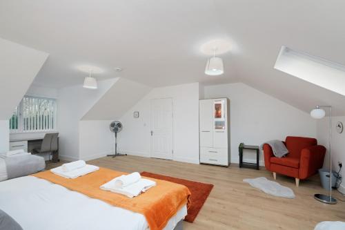 a white bedroom with a bed and a red chair at Pinewood Studios, Iver Slough Heathrow 1 & 2 Bedroom Apartments with Parking by Arista Living in Slough