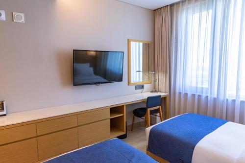 um quarto de hotel com uma cama e uma secretária com uma televisão em Gwangyang Lacky Hotel em Gwangyang