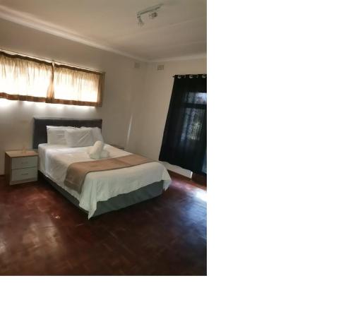 um quarto com uma cama e uma janela em Pumula Holiday Home em Hibberdene