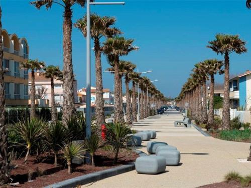 un trottoir bordé de palmiers à côté d'un bâtiment dans l'établissement Studio cabine avec piscine et parking à Marseillan - FR-1-326-607, à Marseillan