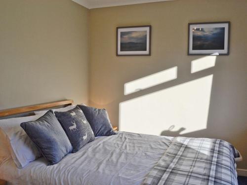a bedroom with a bed with two pictures on the wall at Glencairn Rd, in Langbank