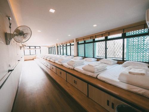 a long row of beds in a room with windows at More than Sleep Hostel Pak Chong-Khao yai in Pak Chong