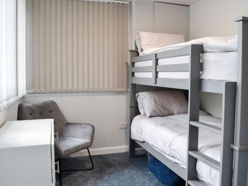 a dorm room with a bunk bed and a chair at 3 Ladyknowe - Uk39969 in Moffat