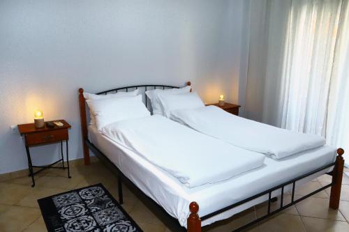 a bedroom with two beds with white sheets and two candles at Ourania Apartment in Drama