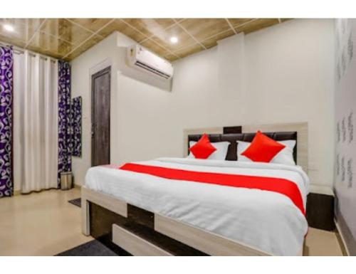 a bedroom with a large bed with red pillows at Vishesh Resort, Lucknow in Lucknow