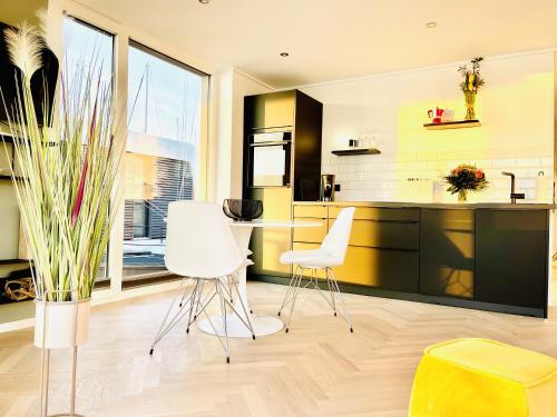 a kitchen with white chairs and a table at Floating Home Nr 1a in Laboe