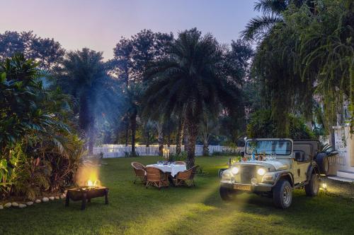 an old jeep parked in a yard with a table at Jaagir Manor, Dudhwa - IHCL SeleQtions in Paliā Kalān