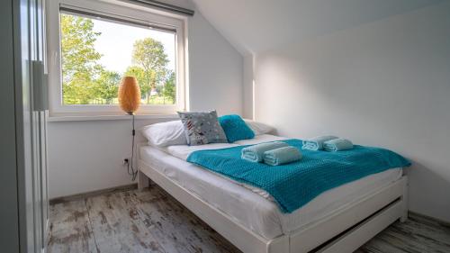 1 dormitorio con cama con sábanas azules y ventana en Turkusowy Klif, en Jastrzębia Góra