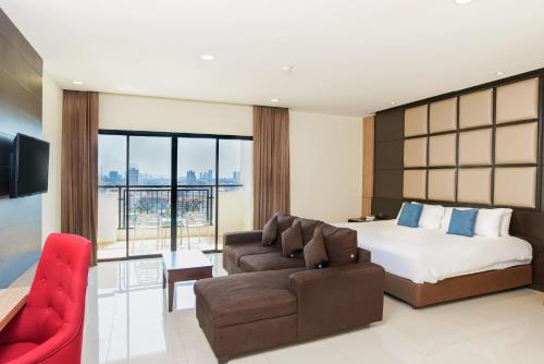 Grand Palazzo Hotel - SHA Extra Plus في باتايا سنترال: غرفه فندقيه بسرير واريكه
