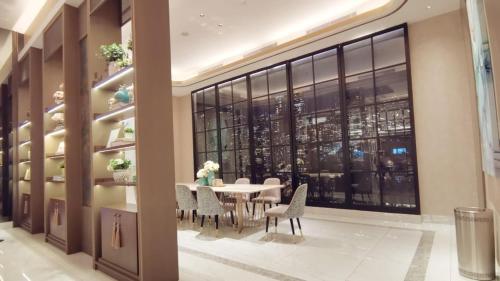 uma sala de jantar com mesa e cadeiras e uma grande janela em Benson Tower Surabaya Apartment 2BR by Le Ciel Hospitality em Lontar