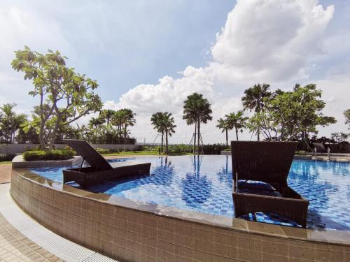 two chairs sitting next to a swimming pool at Benson Tower Surabaya Apartment 2BR by Le Ciel Hospitality in Lontar