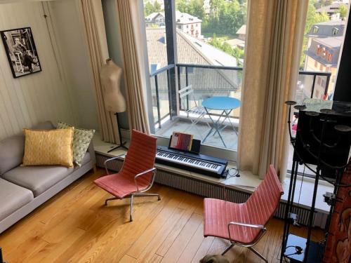 een woonkamer met een bank en stoelen en een balkon bij Design loft in Chamonix Center in Chamonix-Mont-Blanc