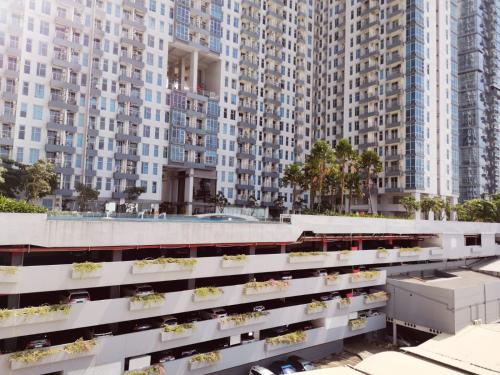 an apartment building with plants on it in front of tall buildings at Benson Tower Surabaya Apartment 2BR by Le Ciel Hospitality in Lontar