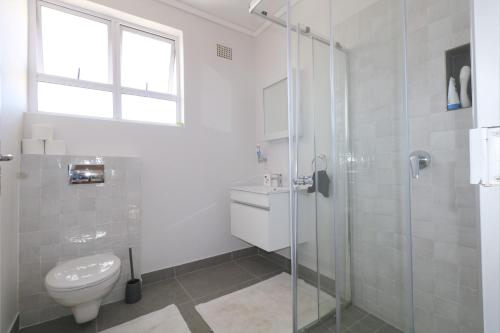 a bathroom with a toilet and a glass shower at Royal House in Muizenberg