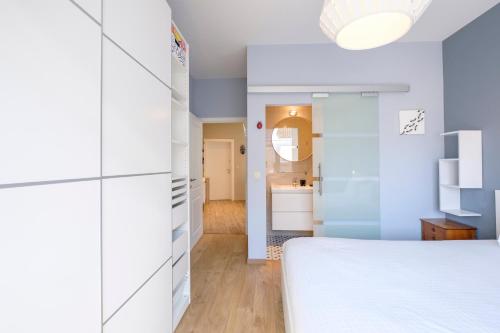1 Schlafzimmer mit einem weißen Bett und einem Badezimmer in der Unterkunft Charmant Appartement 1 chambre avec balcon proximité Cinquantenaire in Brüssel